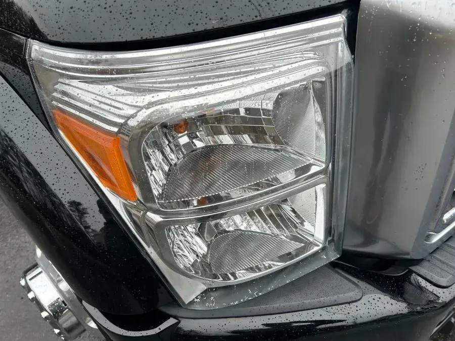 A close up of a black truck 's headlight.