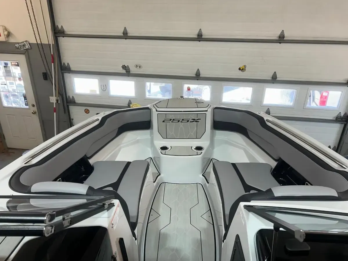 Interior of a white and black speedboat parked in a garage, with a central helm and seating area