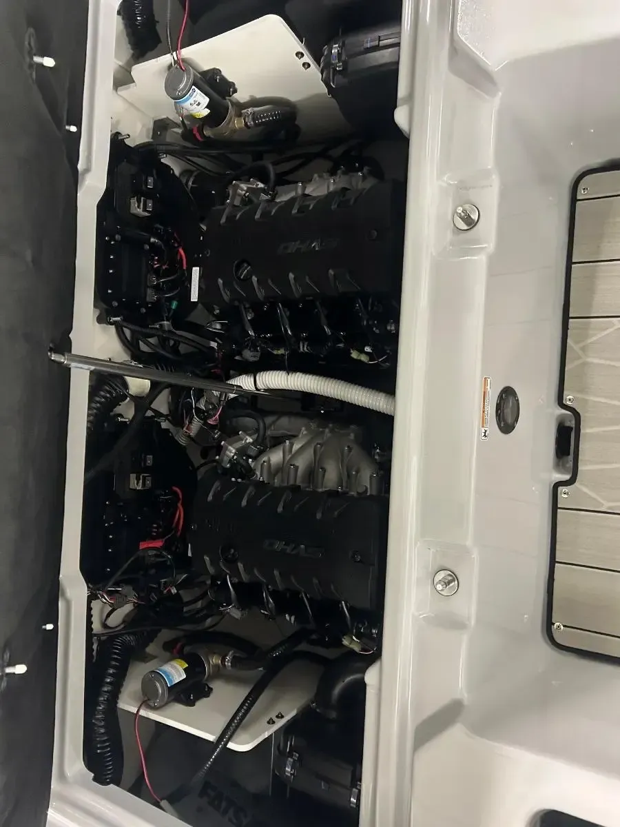 Open compartment with stacked black equipment, wires, and a white device inside a vehicle panel