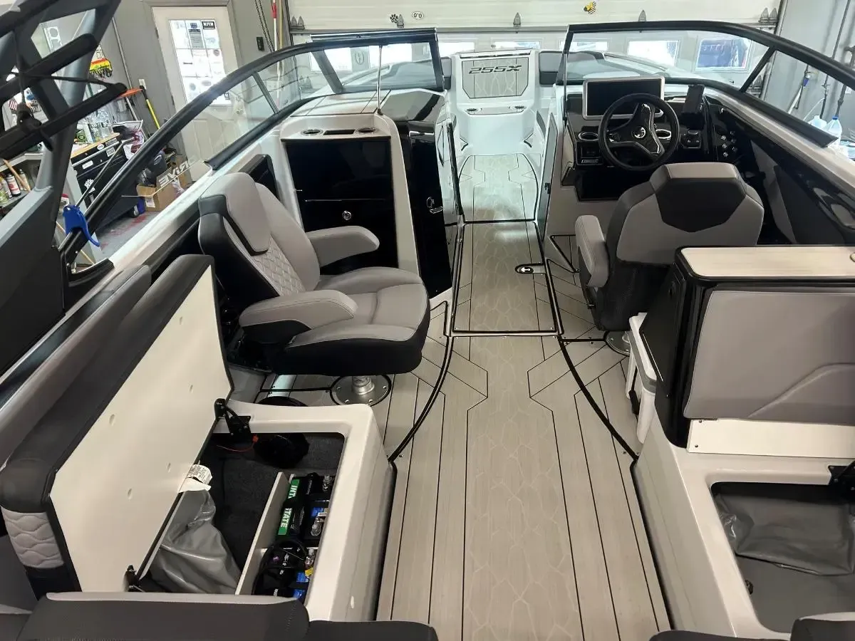 Interior of a white boat cabin with gray seats, helm, and center walkway viewed from the stern