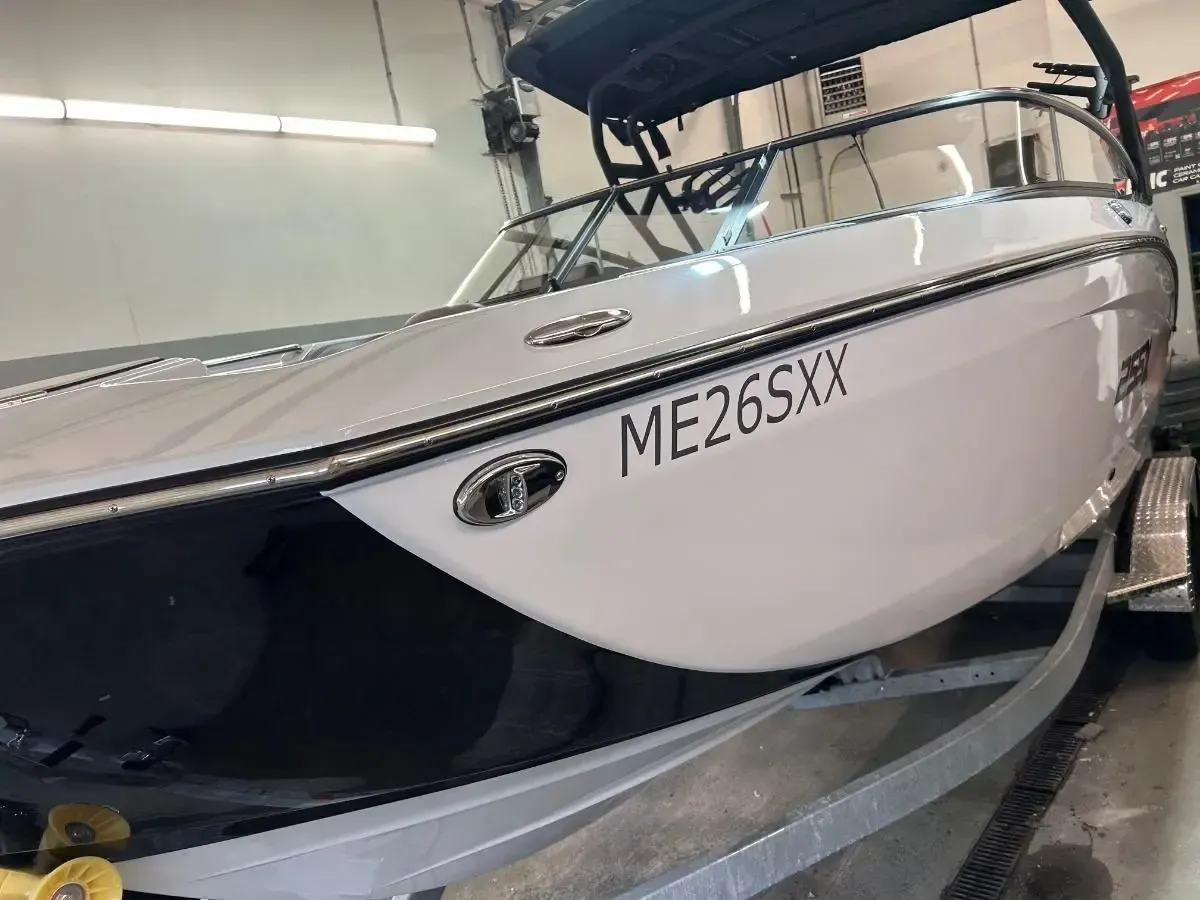 White speedboat on a trailer inside a warehouse, with hull number ME265XX visible.