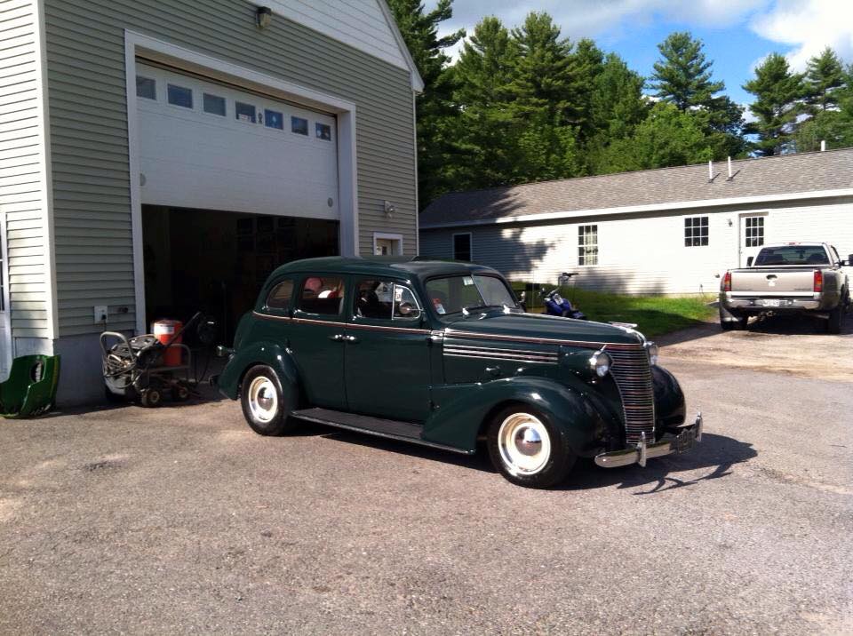 A green car is parked in front of a garage door