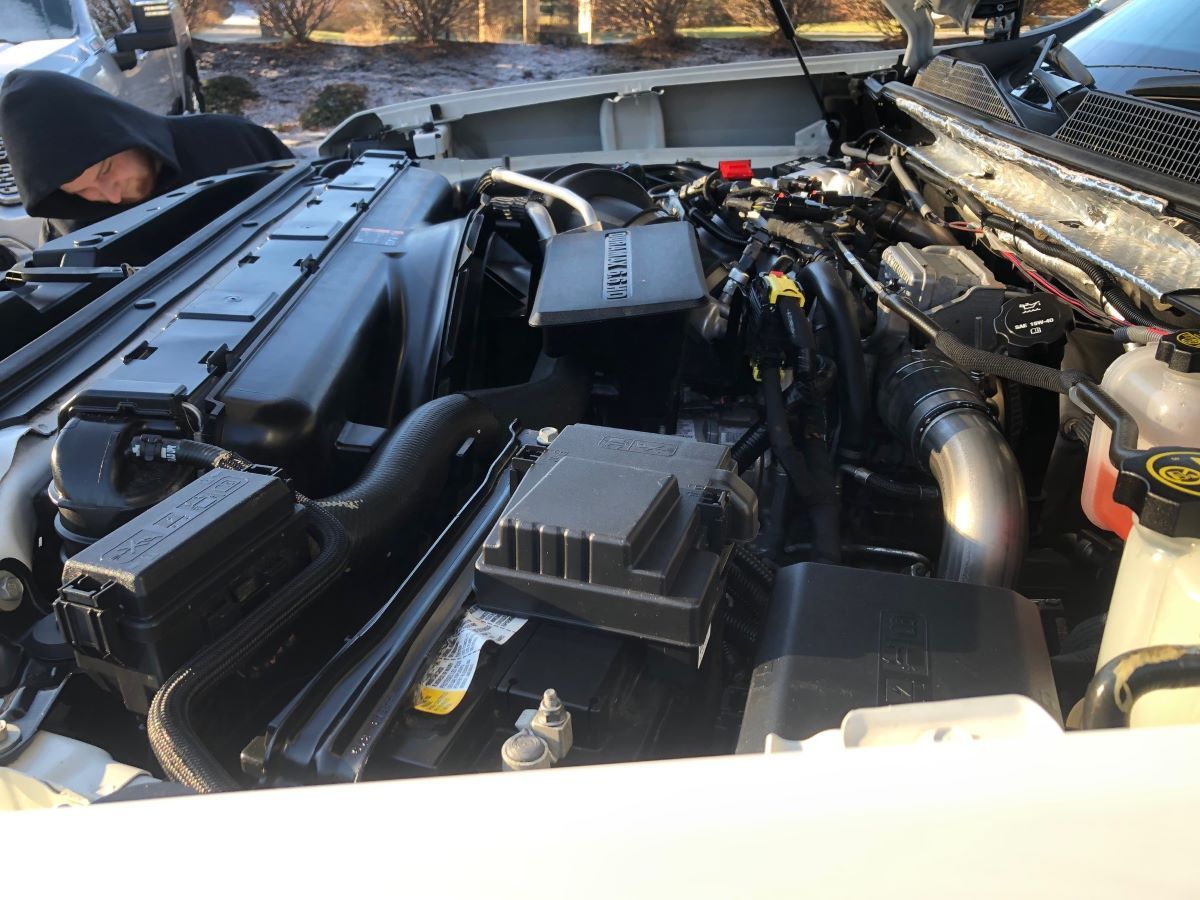 A man is looking under the hood of a car