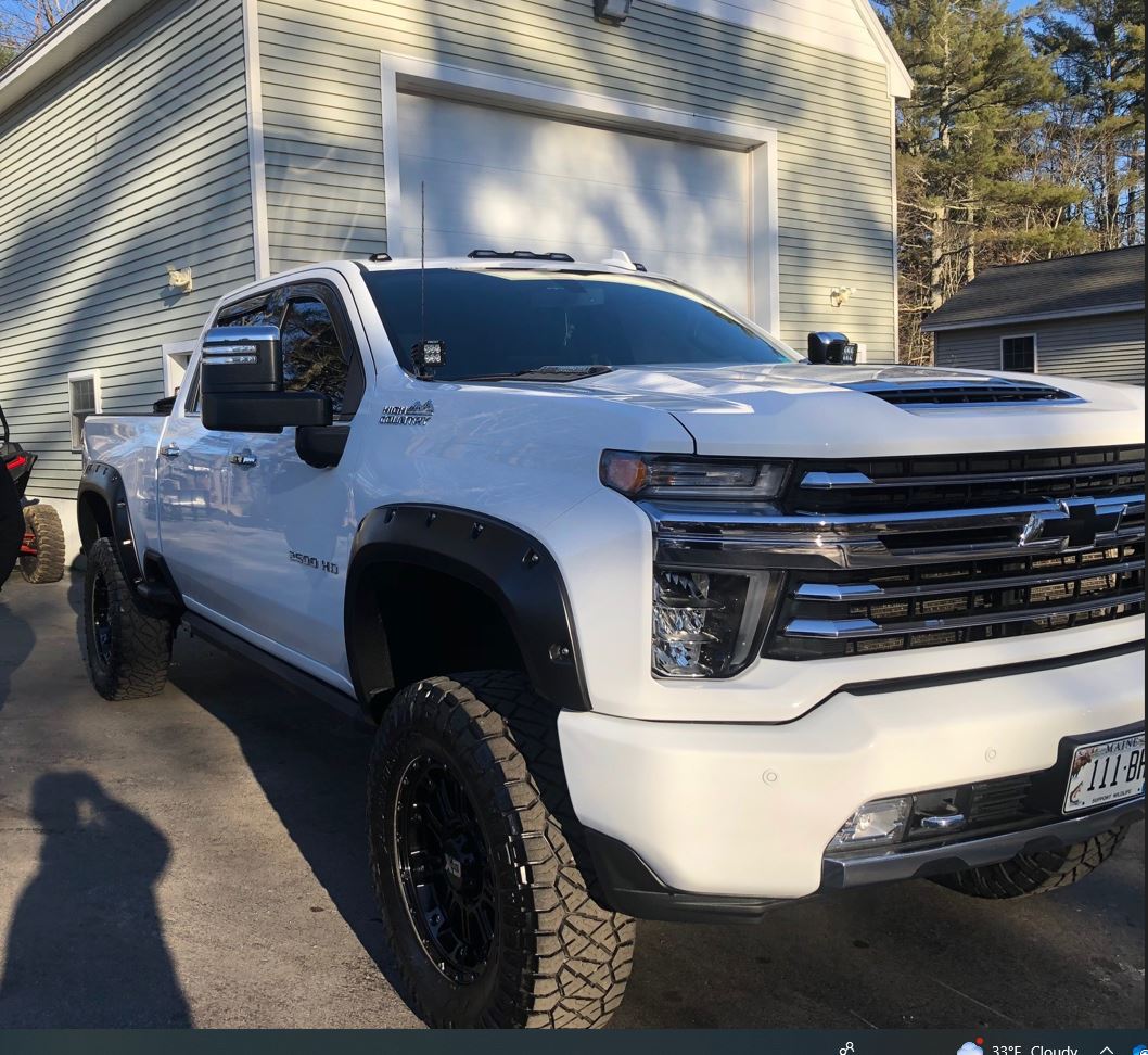 A white truck is parked in front of a garage.