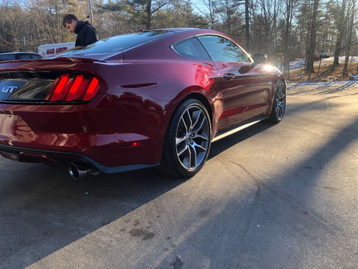 A red ford mustang is parked on the side of the road