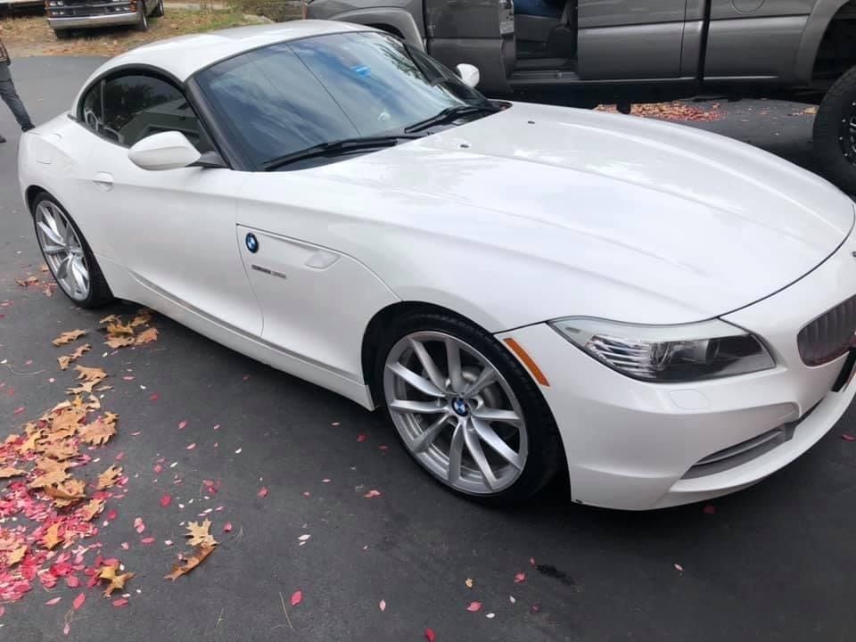 A white bmw z4 is parked on the side of the road.