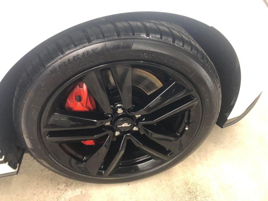 A close up of a car wheel with a red brake caliper.