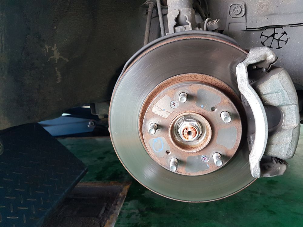 A Man is Working on the Brake of a Car — H.M. Mechanical in Cambooya, QLD