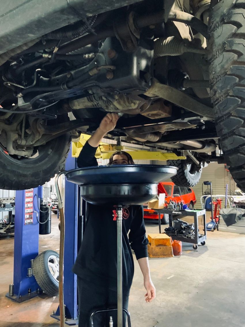A man is working under a car in a garage — H.M. Mechanical in Drayton, QLD
