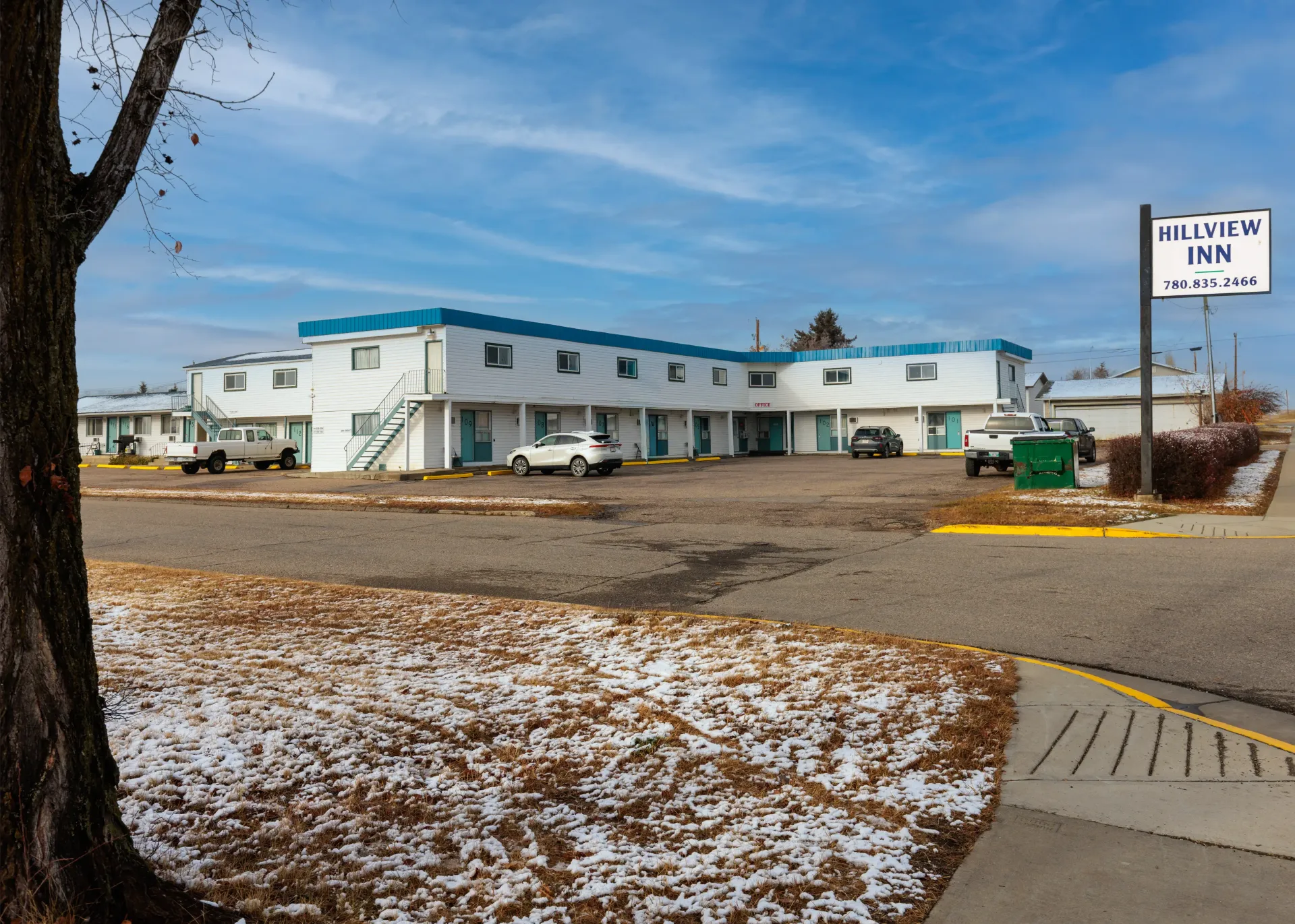 A low-rise white motel building with a blue roof, under a blue sky, with a sign reading 