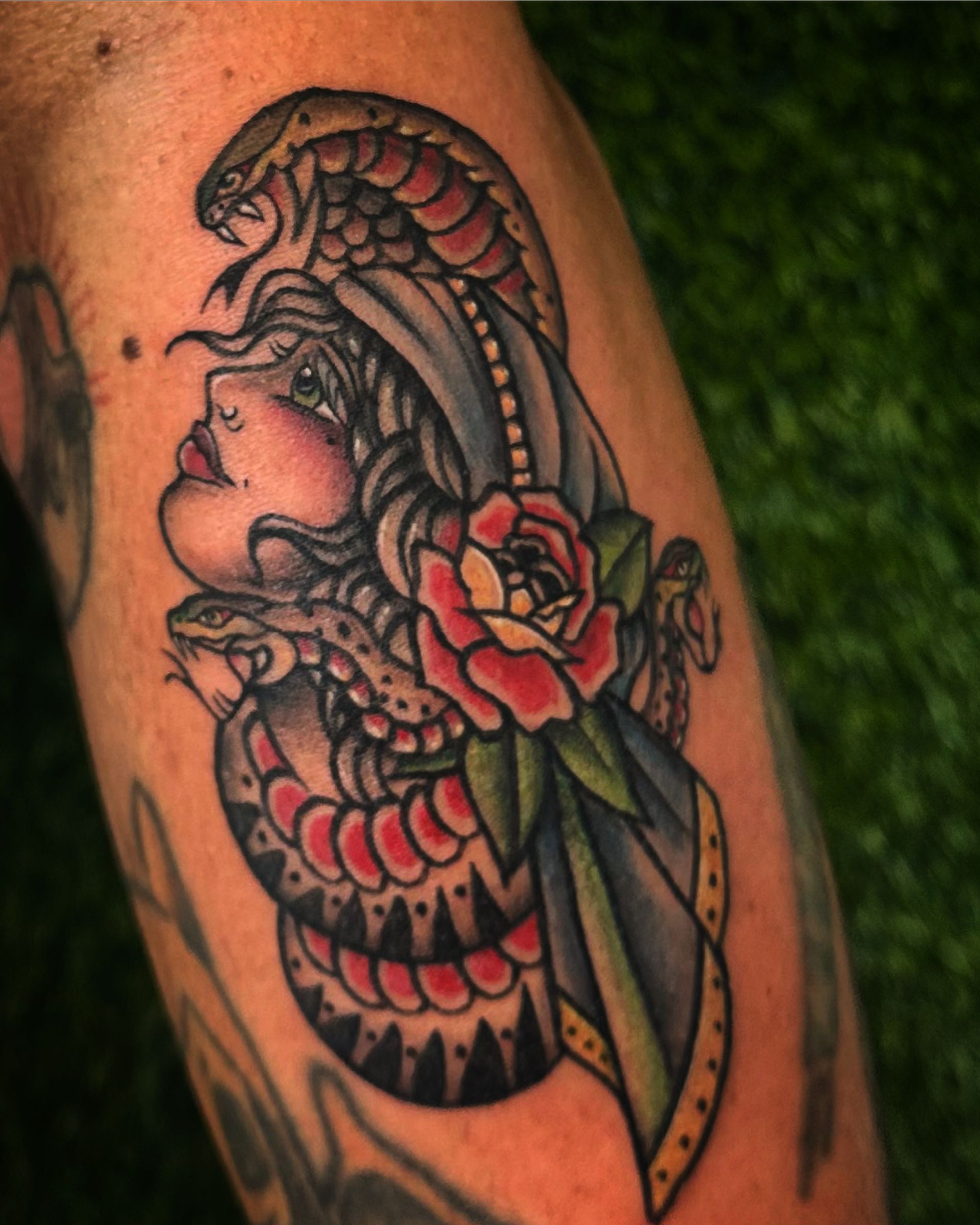 Tattoo of a woman's profile, with snakes and a flower in traditional style.