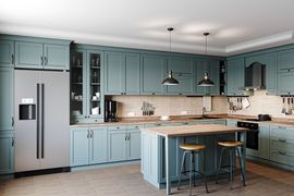 A modern kitchen with muted blue-green cabinets, a stainless steel refrigerator, and a wooden island with two stools.