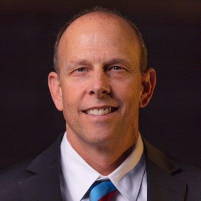 A man in a suit and tie is smiling for the camera.