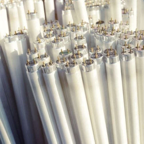 A bunch of white fluorescent light bulbs are stacked on top of each other.