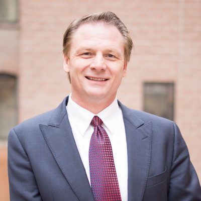A man in a suit and tie is smiling for the camera
