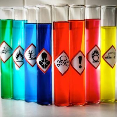 A row of test tubes with different colored liquids and warning signs on them