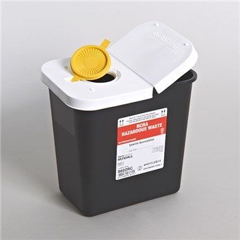 A black sharps container with a yellow lid is sitting on a table.