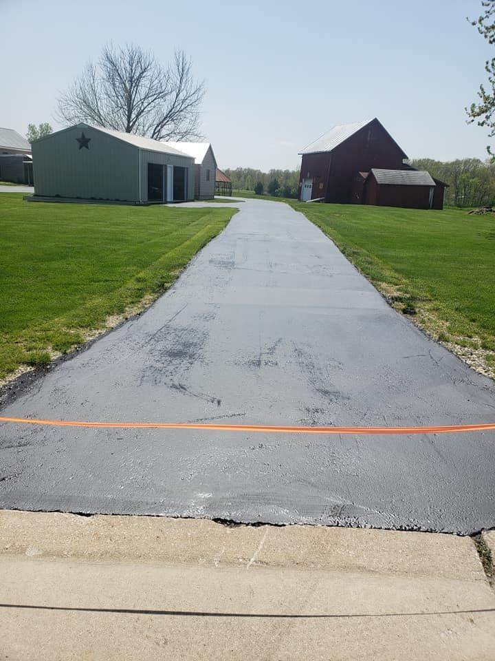 A driveway with a red barn in the background