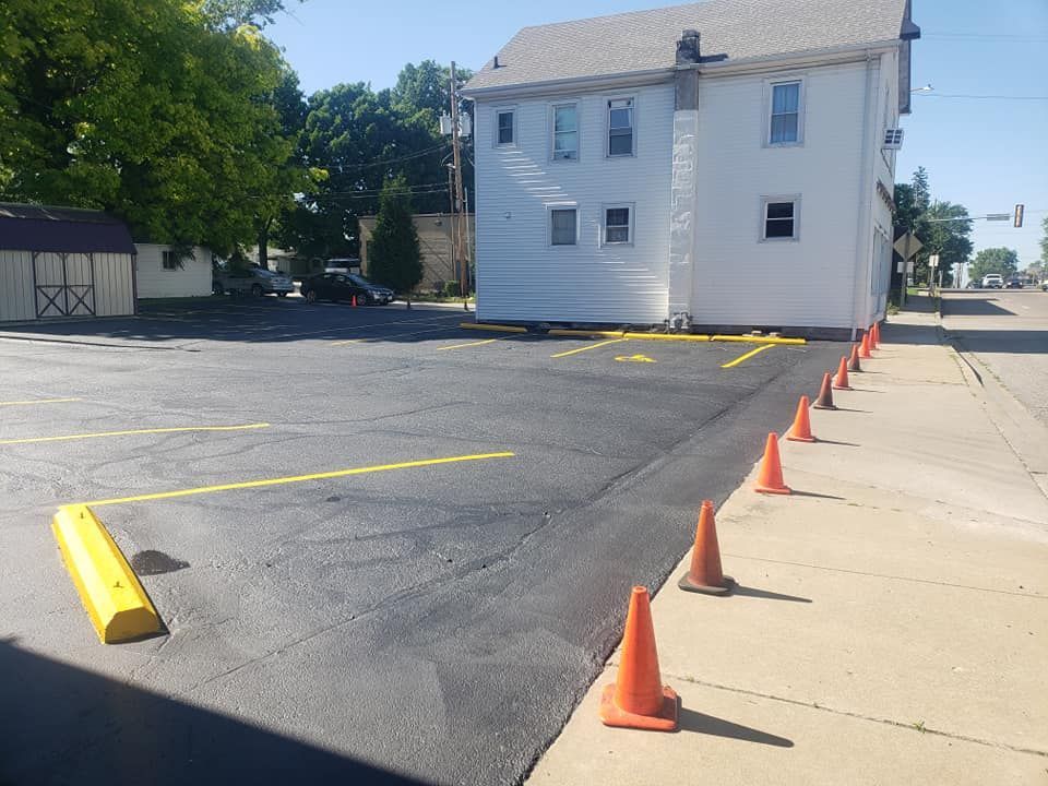 A parking lot with orange cones and a yellow curb