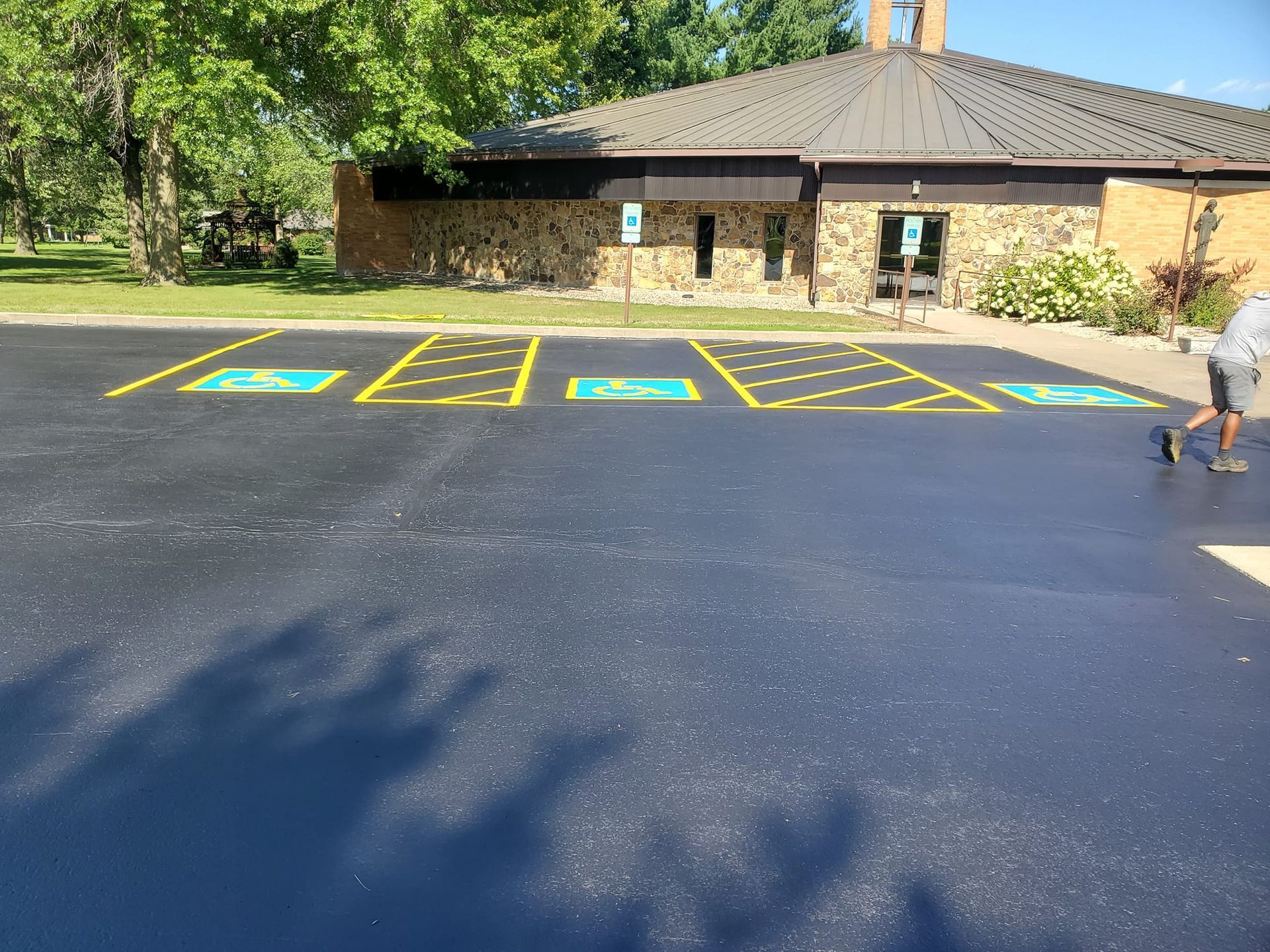 A man is walking down a parking lot in front of a building.
