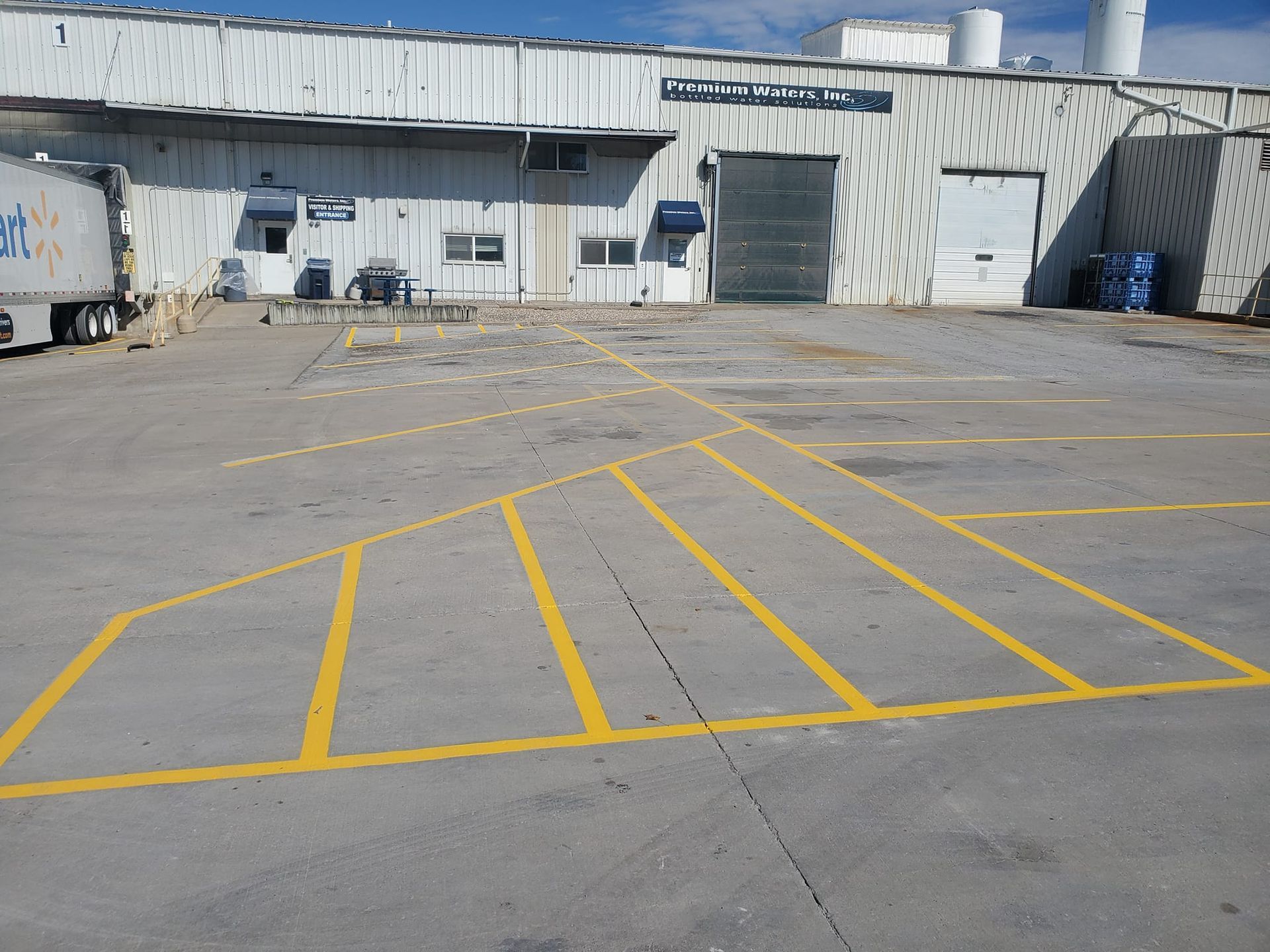 A white building with a blue truck parked in front of it