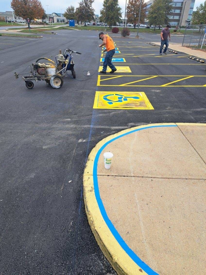 A man is painting a handicapped parking space in a parking lot