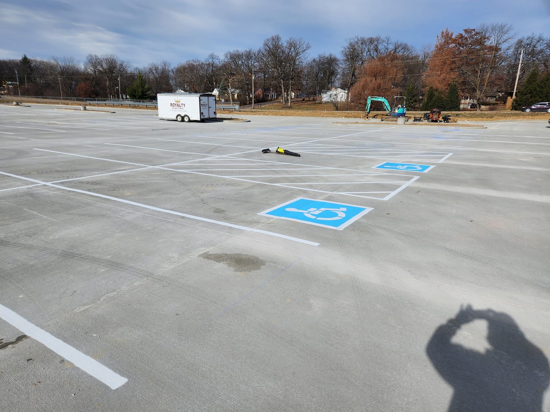 A shadow of a person is cast on a parking lot