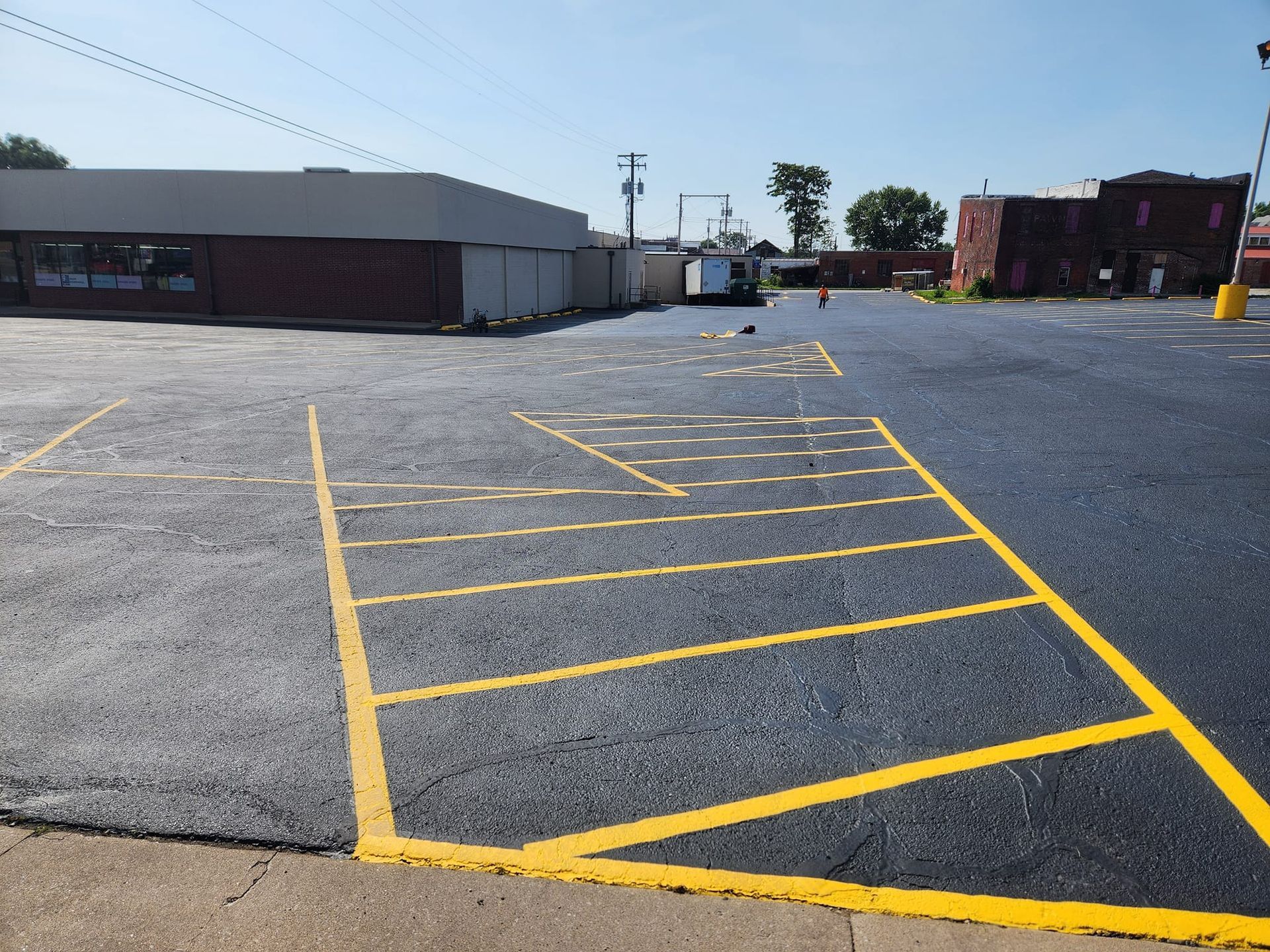 A parking lot with yellow lines and a building in the background