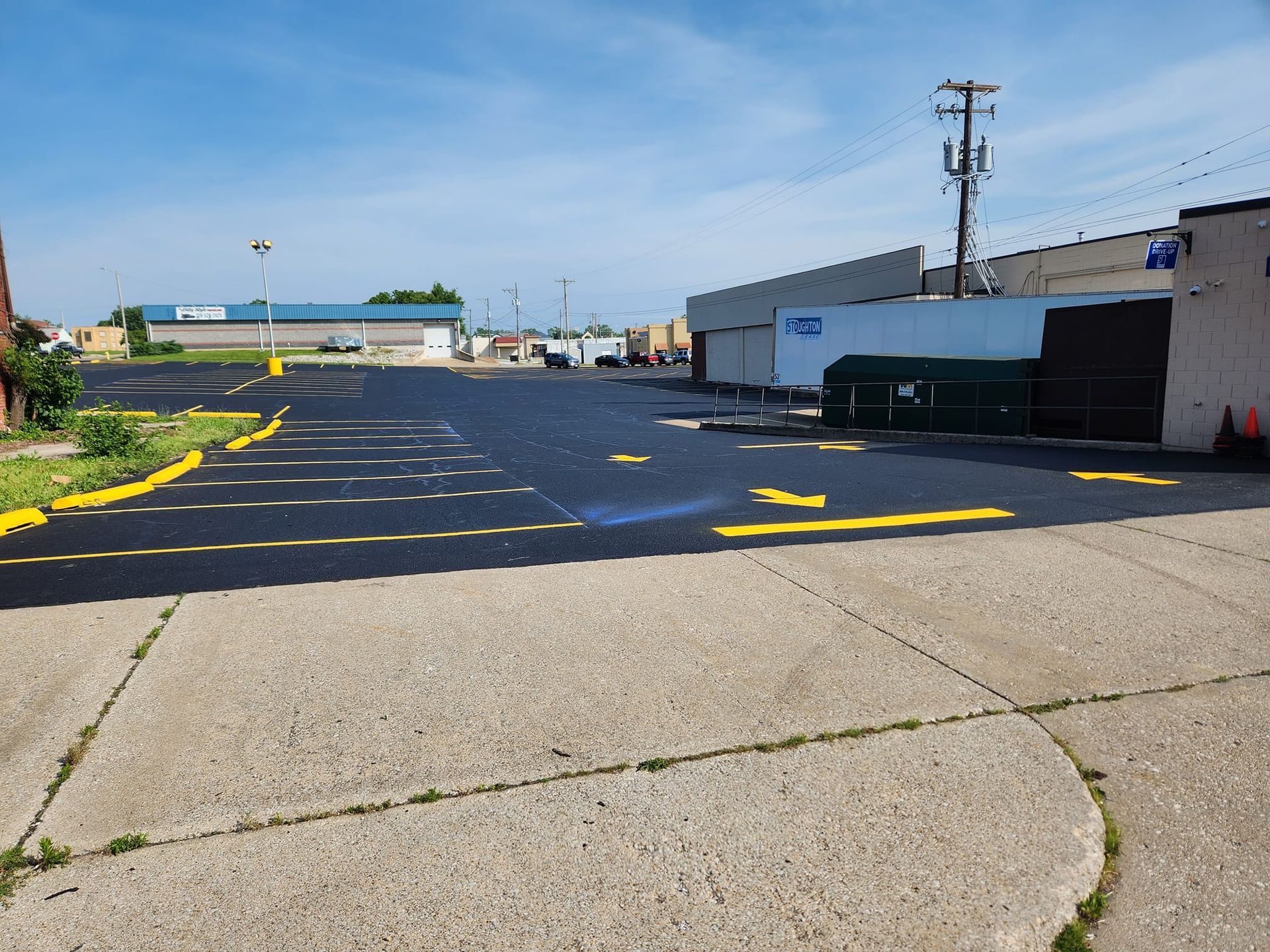 A parking lot with a sidewalk and a building in the background