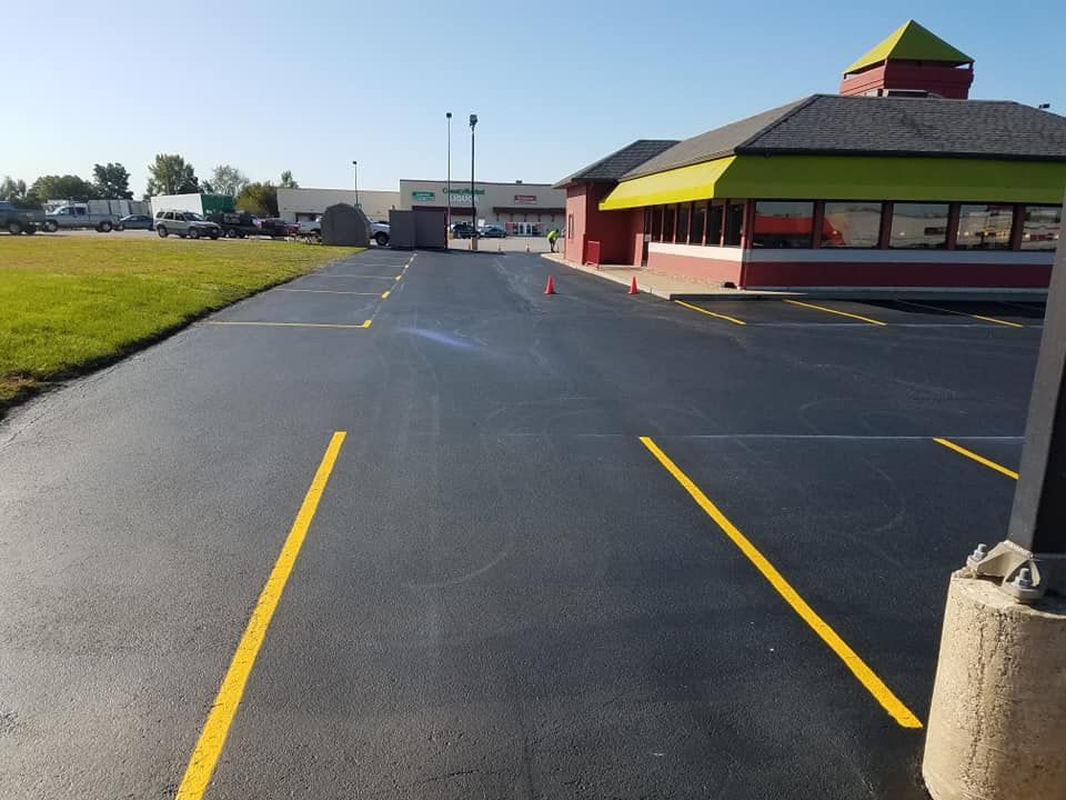 A parking lot with yellow lines and a building in the background