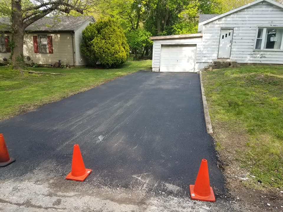 A driveway with two orange cones in front of a house.