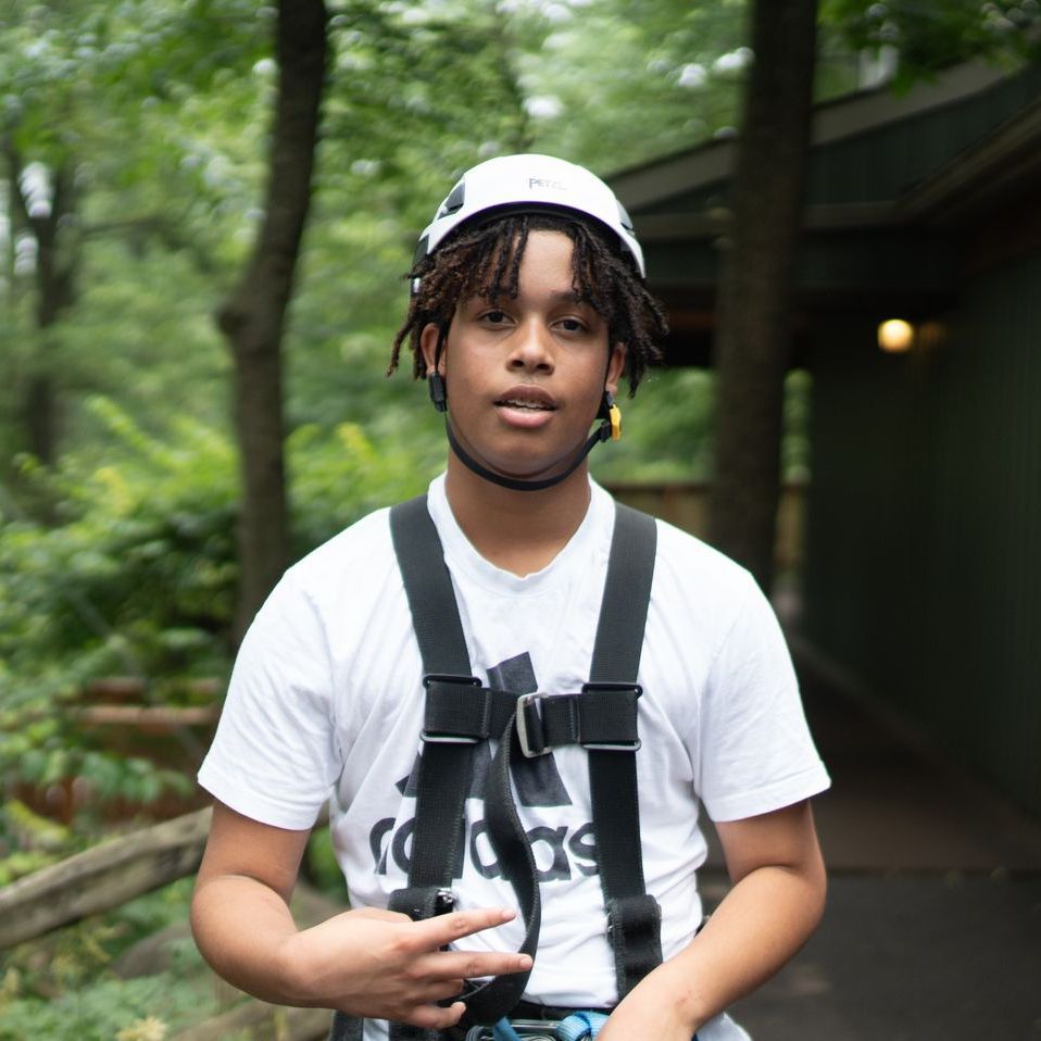 A young man wearing a helmet and a white adidas shirt