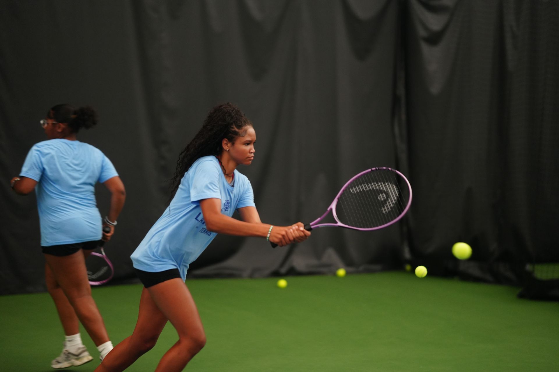 A group of children are playing tennis on a tennis court.