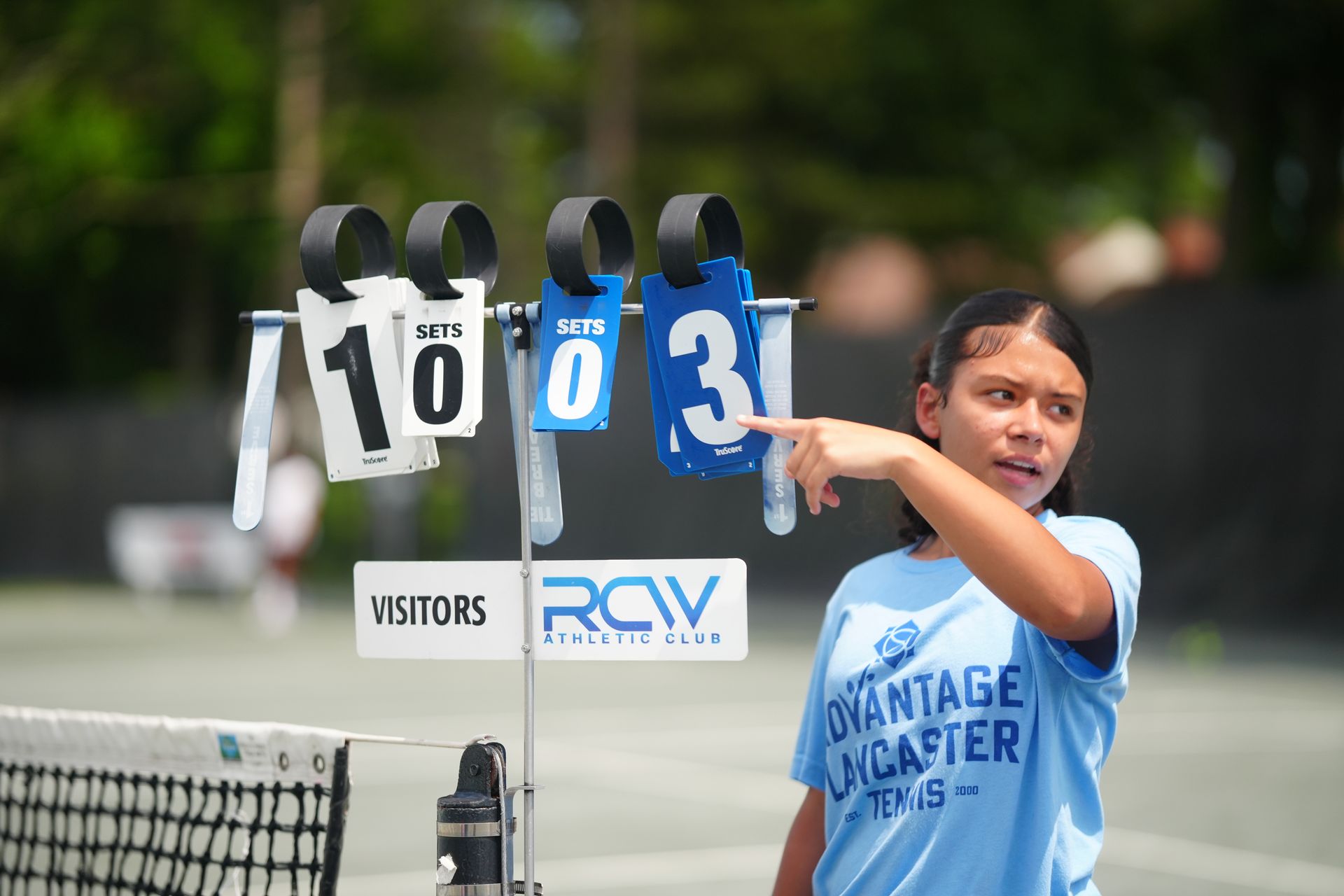 A group of people are standing on a tennis court holding tennis rackets.