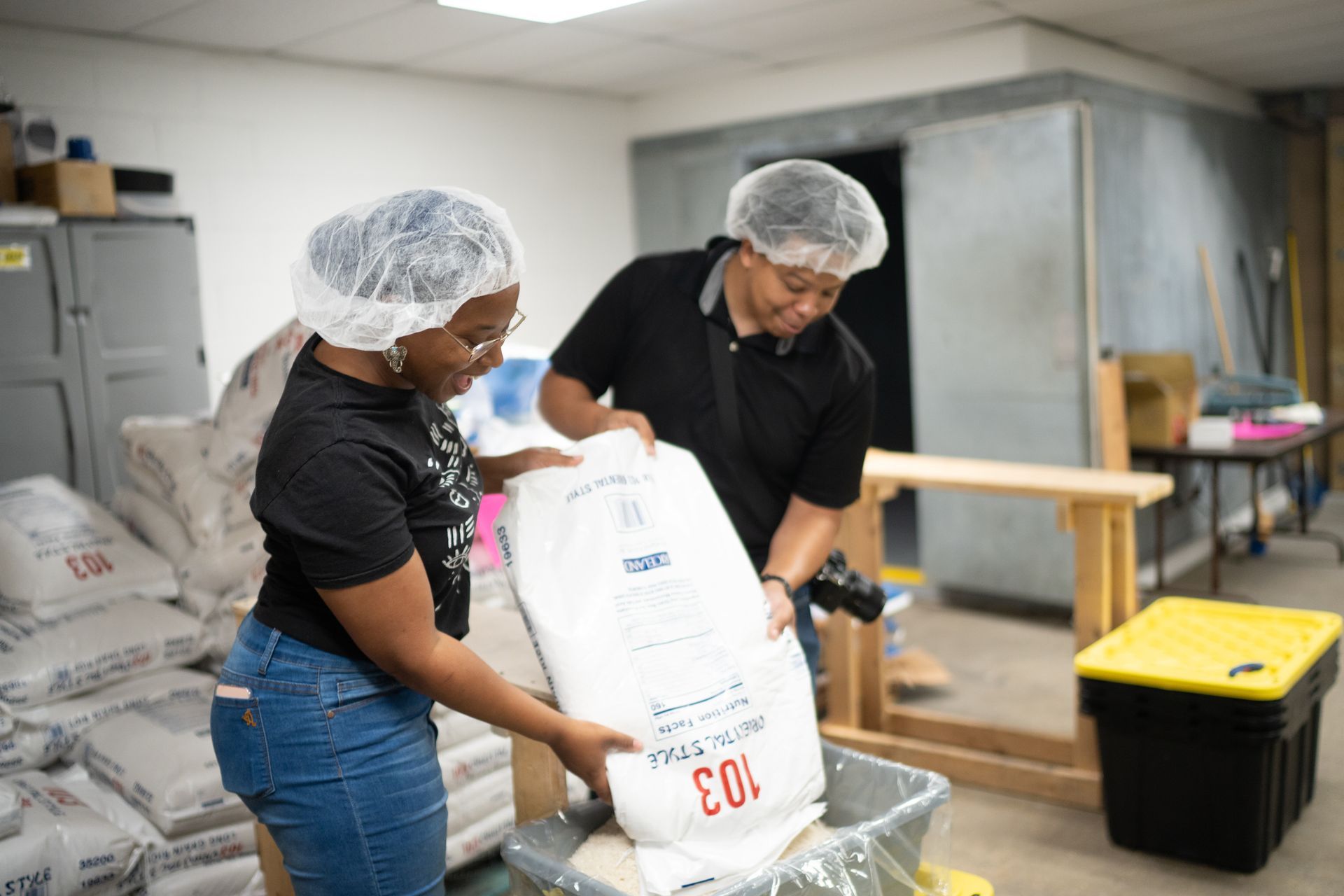 A man and a woman are loading a bag of flour into a bin.