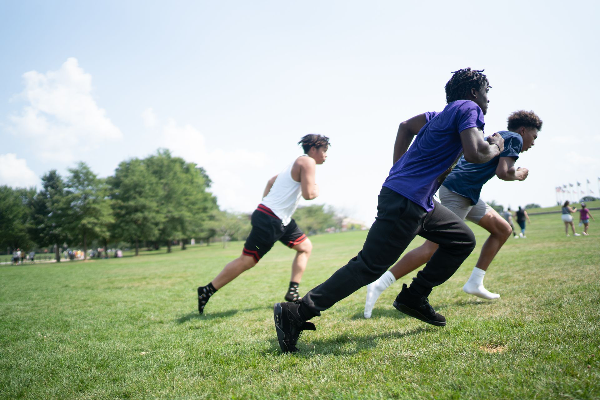 A group of young men are running on a grassy field.
