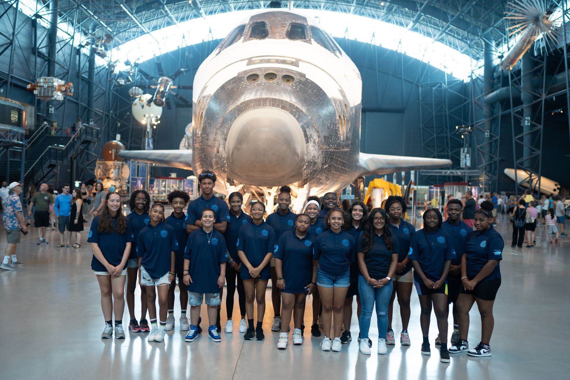 A group of people are posing for a picture in front of a space shuttle.