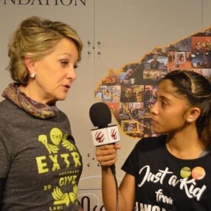 A woman is talking to a young girl who is wearing a shirt that says just a kid