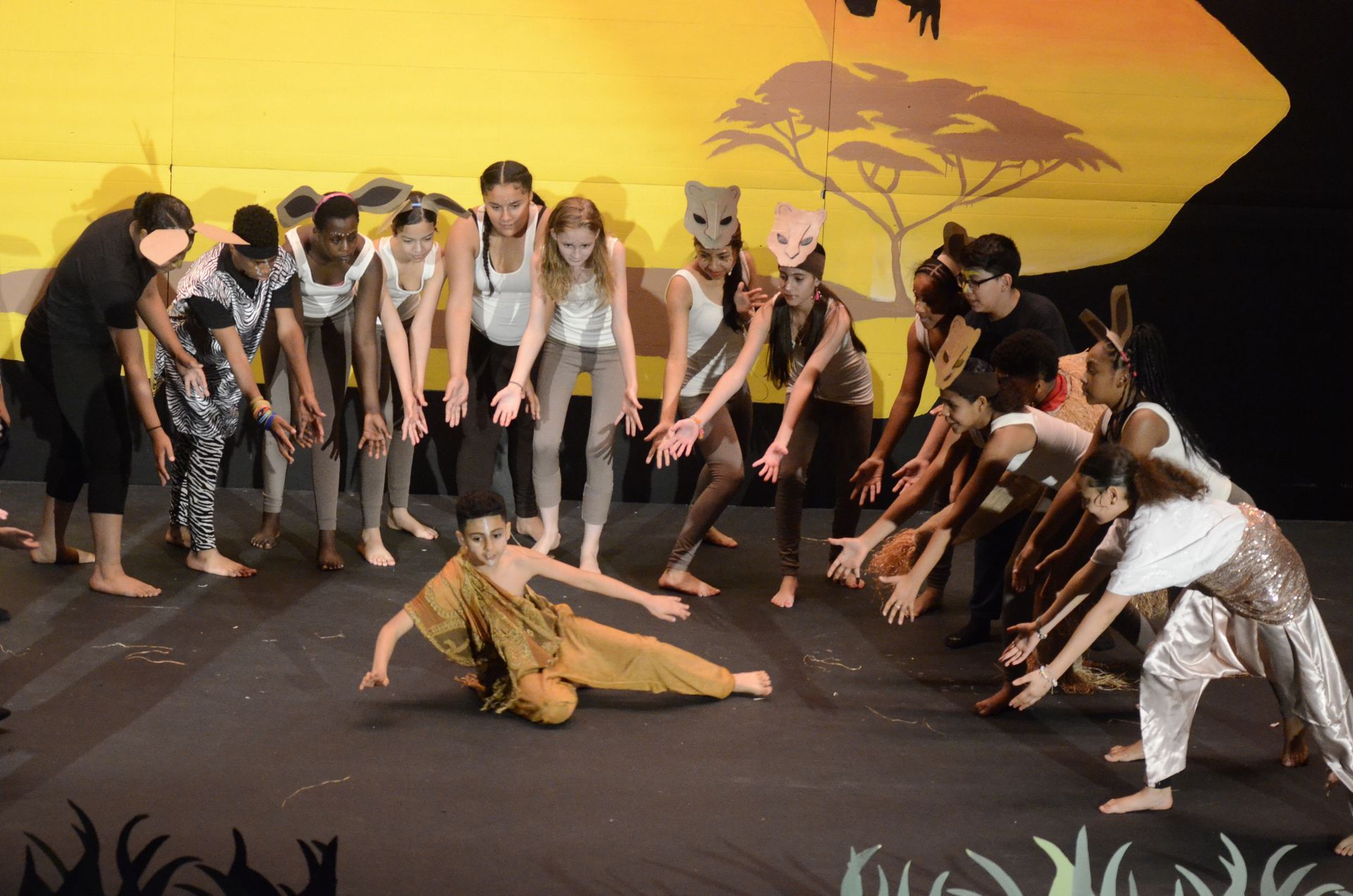 A group of people are dancing on a stage with a lion in the background