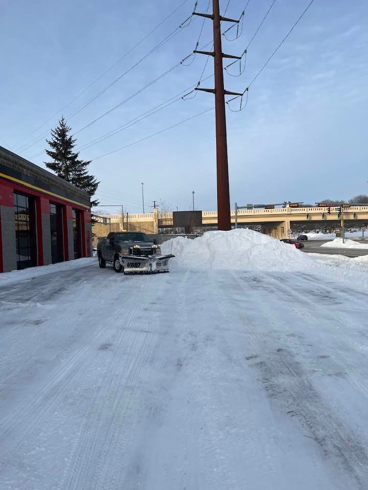 A truck is driving down a snowy road next to a power pole.