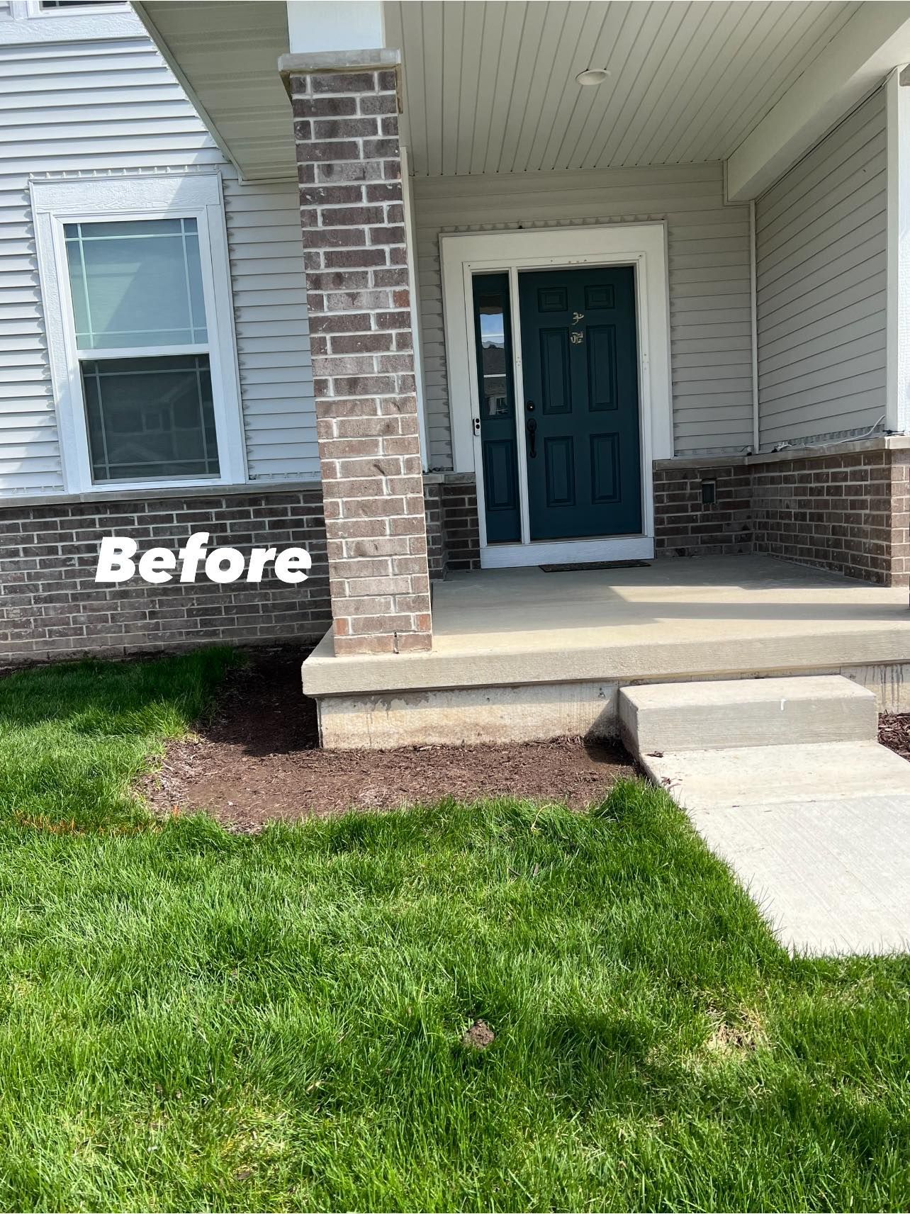 A before picture of a house with a brick porch and a blue door.
