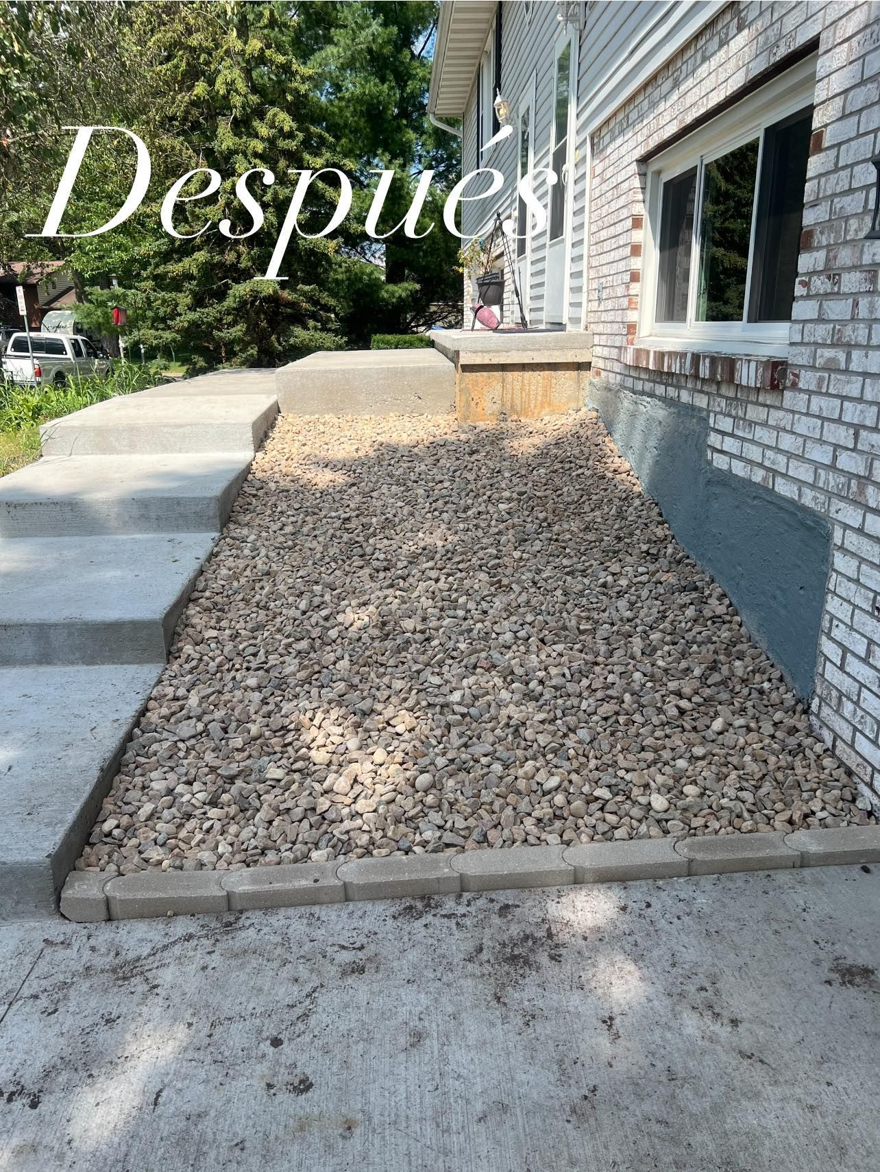 A brick house with a sidewalk and gravel in front of it.