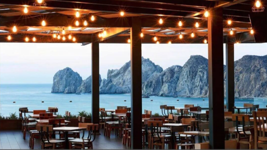 A restaurant with tables and chairs overlooking the ocean