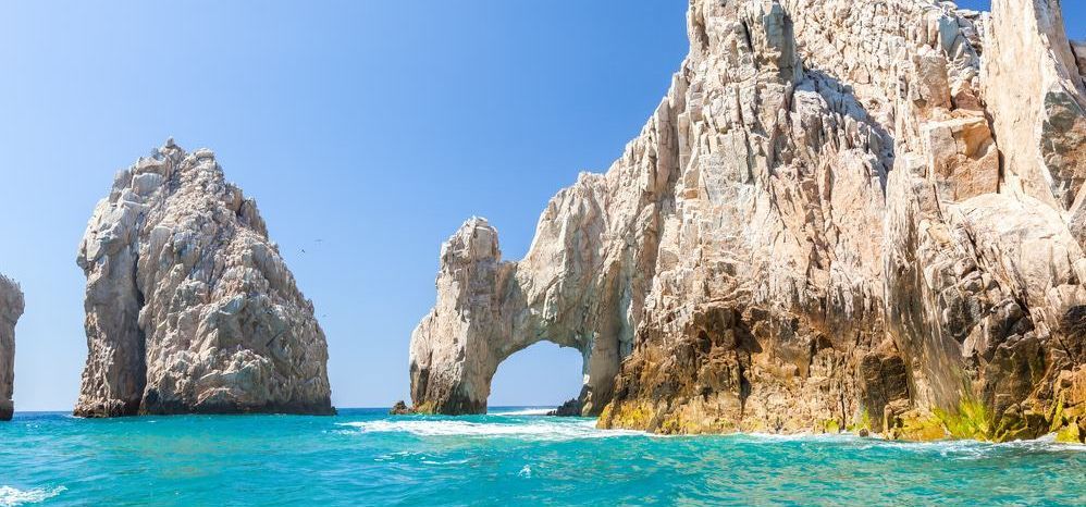 A large rock formation in the middle of the ocean.