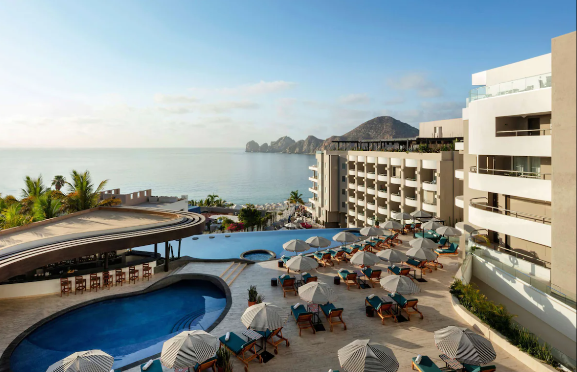 An aerial view of a hotel with a swimming pool and umbrellas.