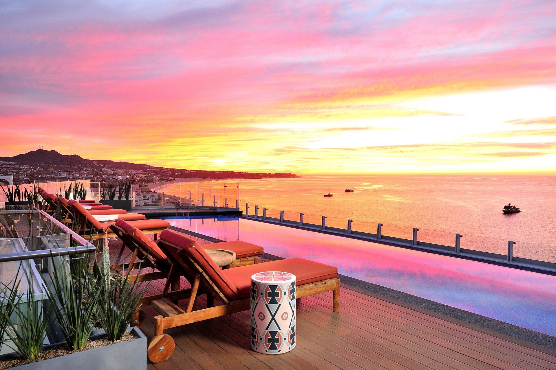 A swimming pool with a view of the ocean at sunset