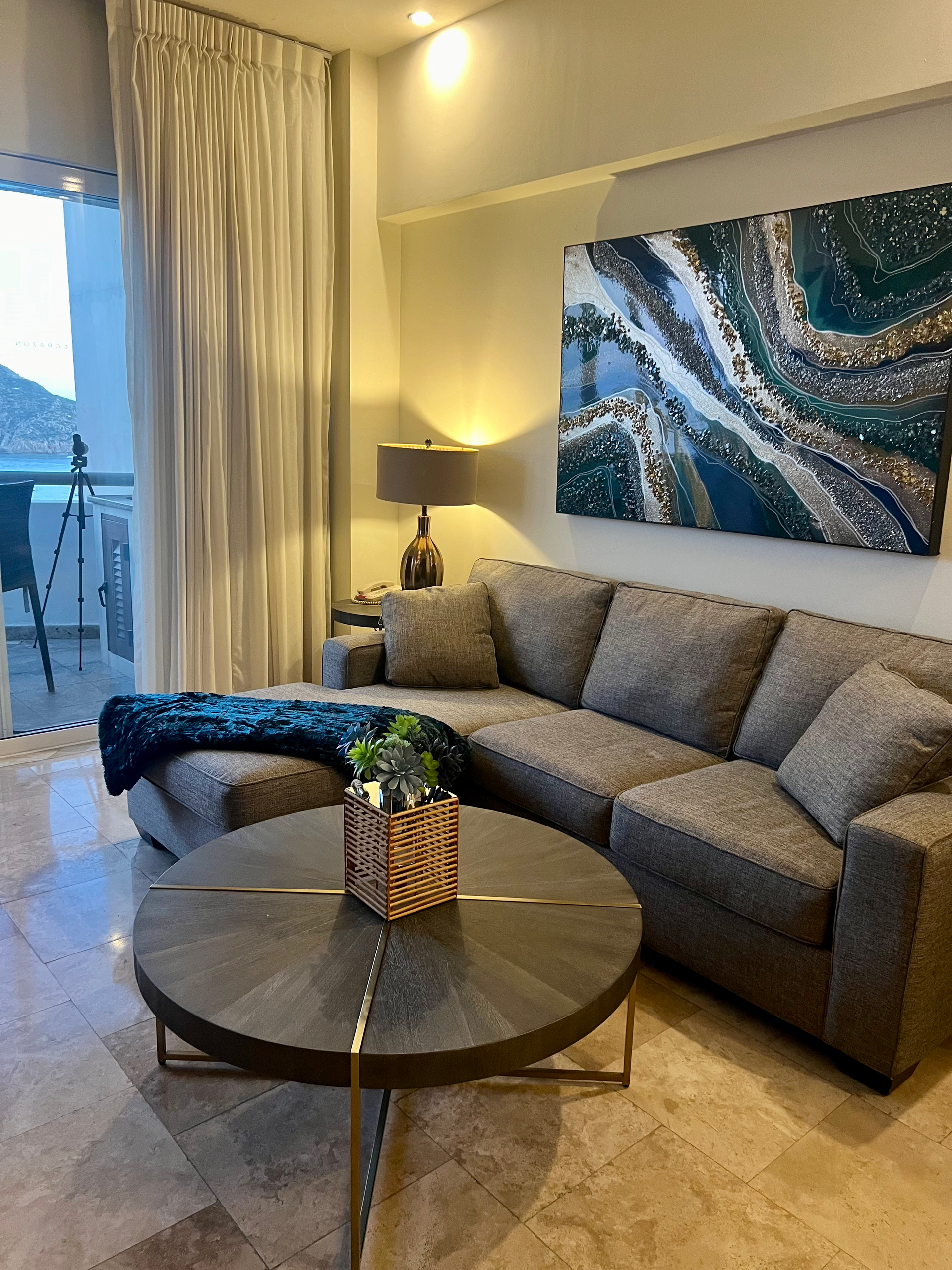 A living room with a couch , coffee table , and painting on the wall.