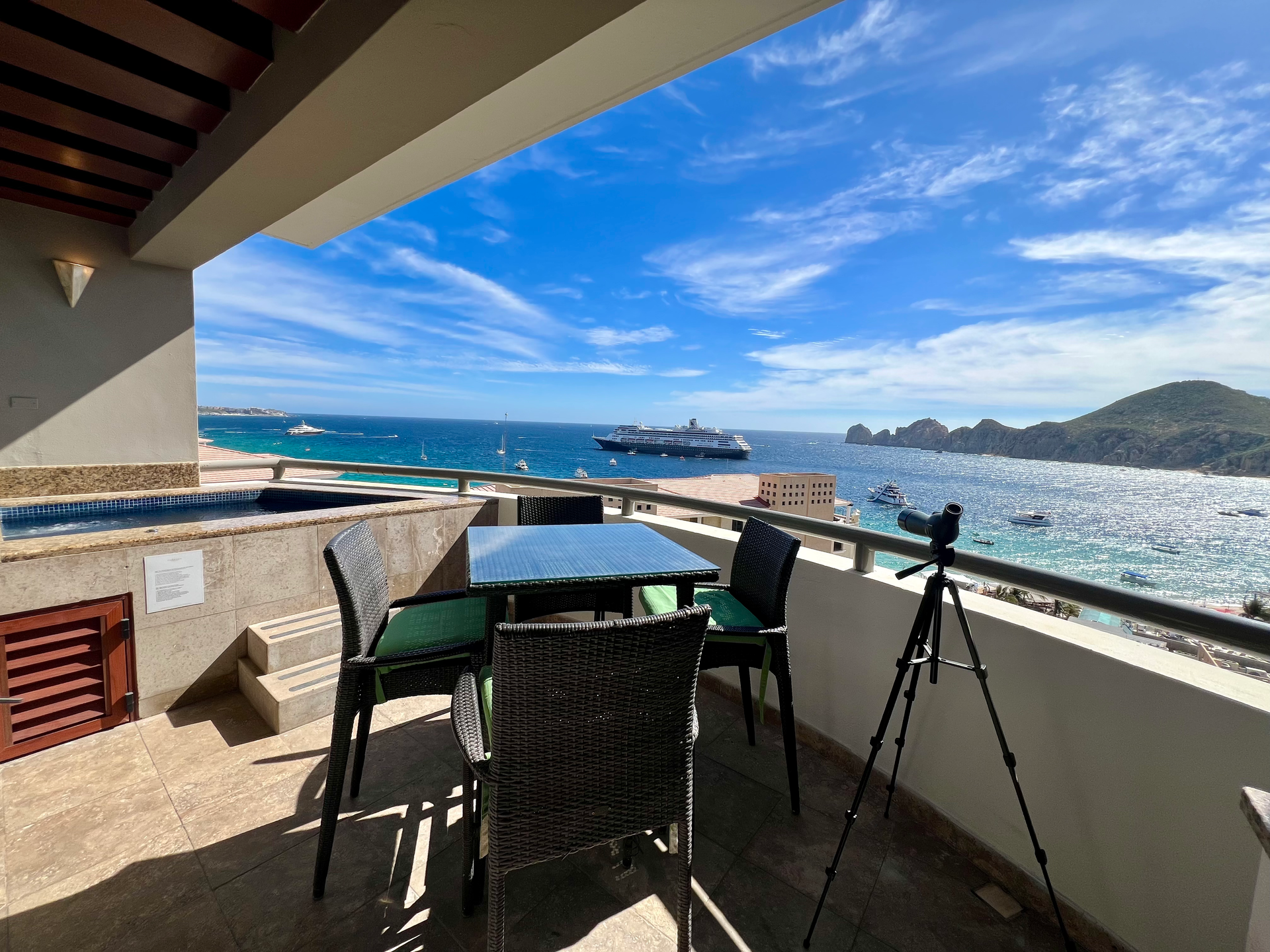 A balcony with a table and chairs overlooking the ocean in Cabo San Lucas