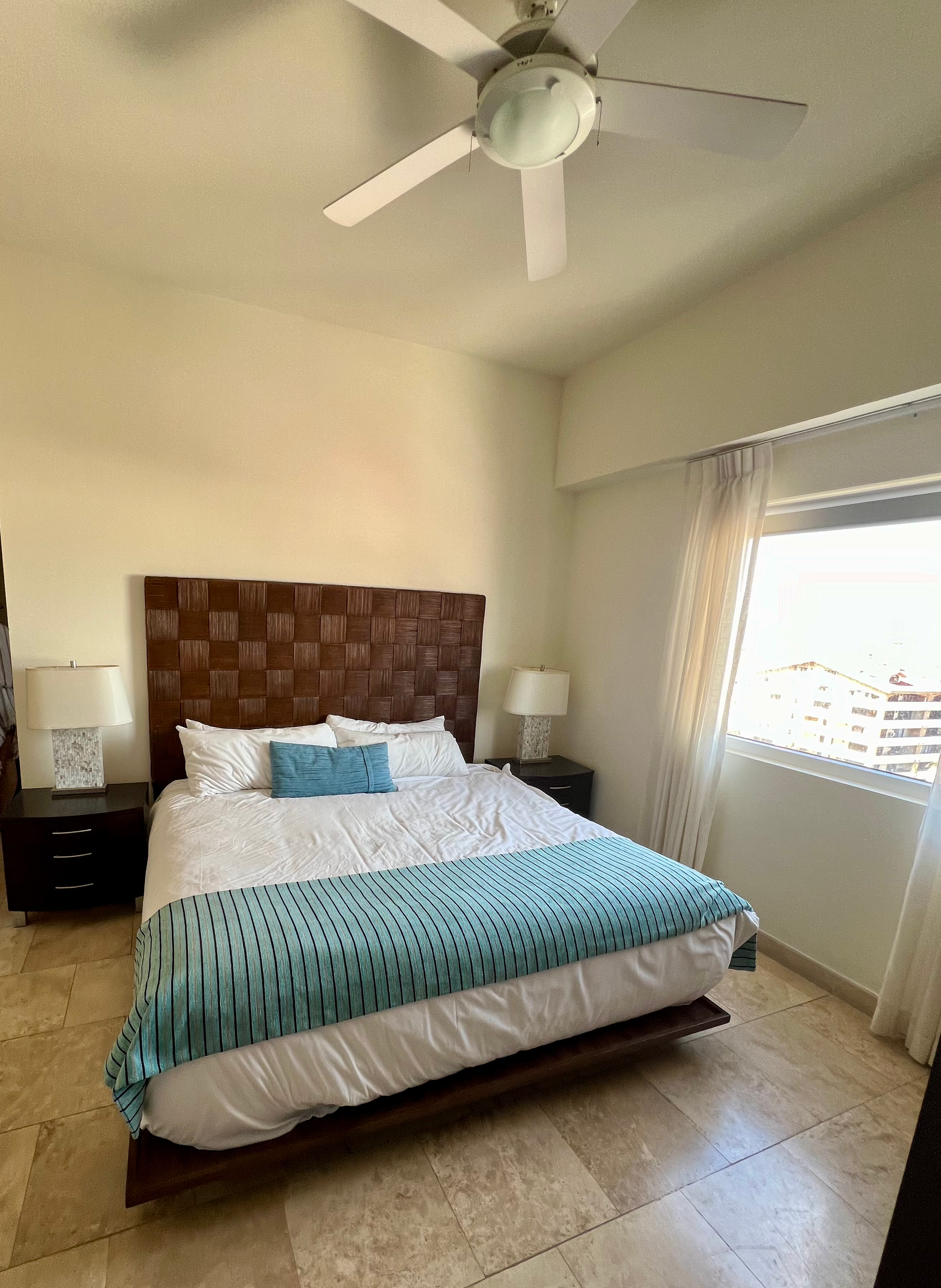 A bedroom with a large bed and a ceiling fan.