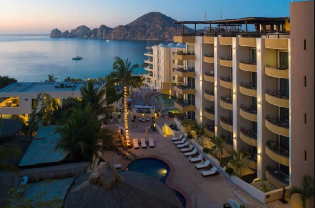 An aerial view of a hotel with a pool in front of it